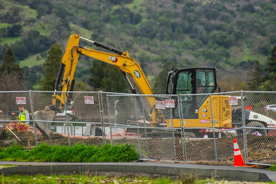 Excavator working at a construction site with perimeter safety barriers — stormwater and erosion compliance context